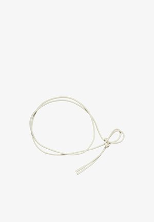 Hvit rund skolisser løst bundet med en enkel knute med plasttupper i begge ender mot en ensfarget bakgrunn.