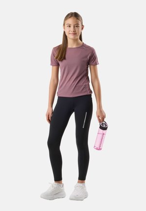 Jong meisje in een mauve shirt met korte mouwen, zwarte legging en witte sneakers, dat een roze waterfles vasthoudt met het label "Swedemount".