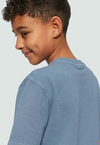 Blaues Baumwoll-T-Shirt mit Rundhalsausschnitt, kurzen Ärmeln und glatter Textur. Verfügt über einen entspannten Schnitt und minimale Nähte für zusätzlichen Komfort.