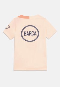 Helles rosa T-Shirt mit kurzen Ärmeln, auf dem Rücken mit "BARÇA" innerhalb eines dunklen runden Rahmens und einem kleinen Logo auf dem linken Ärmel.