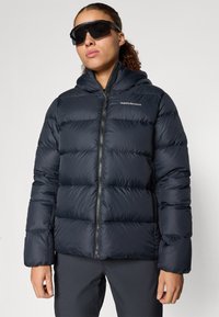 Tumes sinine puffer jope kapuutsiga, millel on horisontaalne tikandimuster ja lukuga eesmine osa. Logo vasakul rinnal. Smooth, läikiv kangastekstuuri.