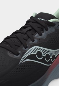 Μαύρο αθλητικό παπούτσι με μαύρα κορδόνια, λευκό ριγωτό λογότυπο στο πλάι και εσωτερική επένδυση σε ανοιχτό μέντα πράσινο.