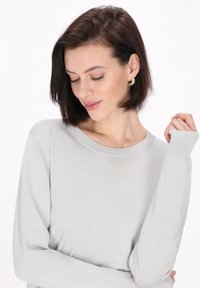 Hellgrauer Langarmpullover mit geripptem Halsauschnitt und Bündchen. Weicher Stoff, lockere Passform, betont dezent die Silhouette des Trägers.