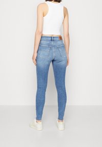 Högmidjade blå jeans i denim, med en figurnära silhuett, två bakfickor och en läderlogg på midjebandet.