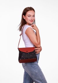 Černá a hnědá kabelka s klopou, texturovaná látka a proužkovaný vzor. Nastavitelný popruh pro nošení na rameni nebo přes tělo.