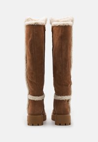Brown suede knee-high boots with white faux fur lining, block heels, and a rugged sole. Features side zip for easy wear.