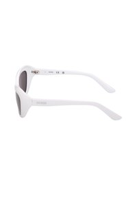 Lunettes de soleil blanches à monture œil de chat avec verres foncés, logo "GUESS" sur les branches, vues de côté sur fond blanc.