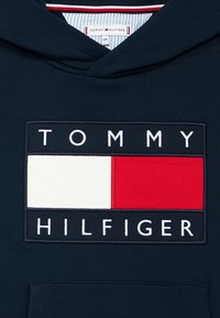 Navy hoodie featuring a prominent rectangular logo with "TOMMY" on top, "HILFIGER" below, and red and white color blocks in the center.