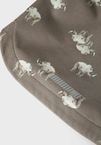 Tessuto grigio con un motivo di rinoceronti ripetuto, caratterizzato da una texture morbida e bordi curvi. Un accento a strisce orizzontali in diverse tonalità corre lungo un lato.