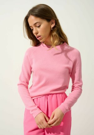 Roze lange mouwen trui van zacht gebreid materiaal met een ronde halslijn en geribbelde manchetten, gecombineerd met bijpassende roze relaxed-fit broek.