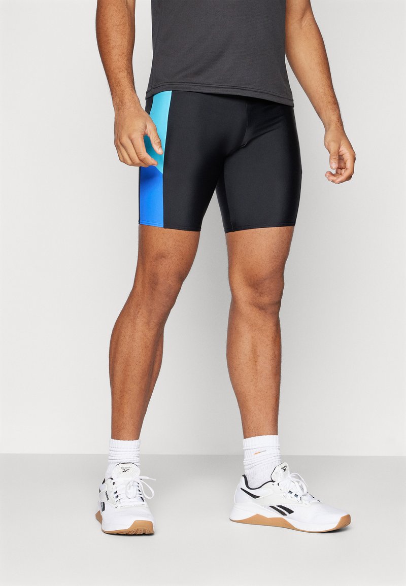 Fekete sportshort, egy oldalán fokozatosan kék panellel. Az anyag simának és rugalmasnak tűnik, alkalmas aktív viseletre.