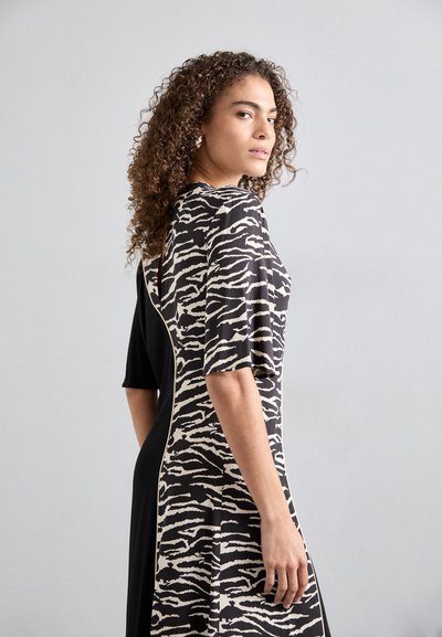 Rochie neagră cu mâneci cu model zebra. Prezintă un guler rotund, mâneci scurte și un design fluid. Material neted, texturat.
