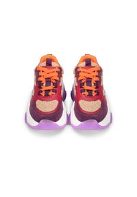Zapatillas coloridas que combinan varios materiales, incluyendo ante morado, pelo marrón claro y suelas de goma blanca. Cuerdas y acentos naranjas presentes.