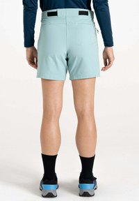 Helle blaue Shorts aus dehnbarem Material, mit flachem Taillenbund, seitlichem Reißverschlussfach und kontrastierenden schwarzen Akzenten. Getragen mit schwarzen Socken und Schuhen.
