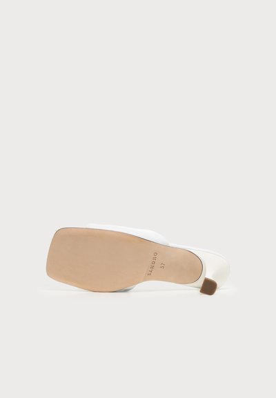 Chaussure mule blanche à talon pour femme, posée sur le côté, montrant la semelle beige avec le nom de la marque et la taille 37 imprimés dessus.