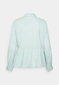 Blusa peplum azul clara com um padrão floral, mangas longas e gola. Feita de um tecido suave e leve.