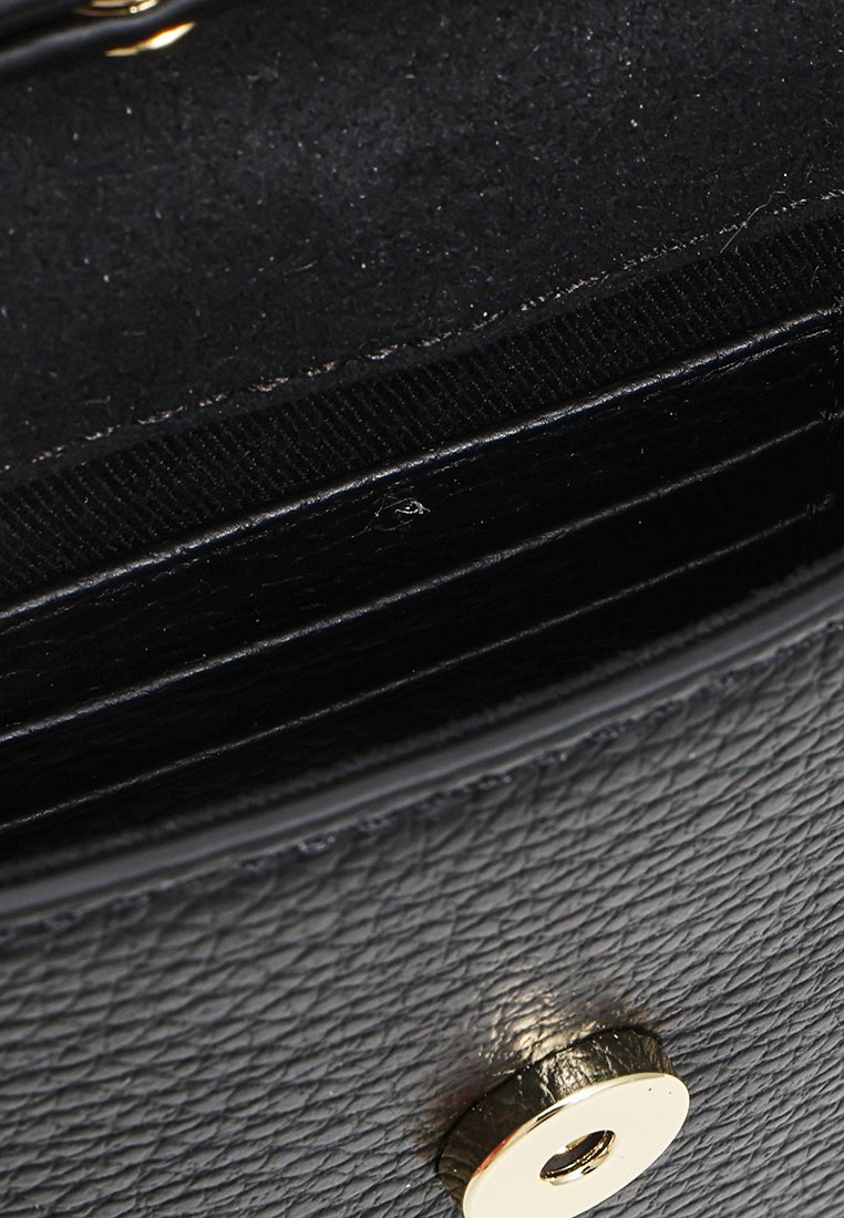 Nahaufnahme einer schwarzen, strukturierten Lederbörse mit einem goldenen Druckknopf und sichtbaren inneren Kartenfächern.