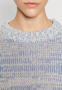 Gebreide trui met een brede hals in blauw en crème, met een gestructureerd verticaal patroon en een geribbelde kraag.