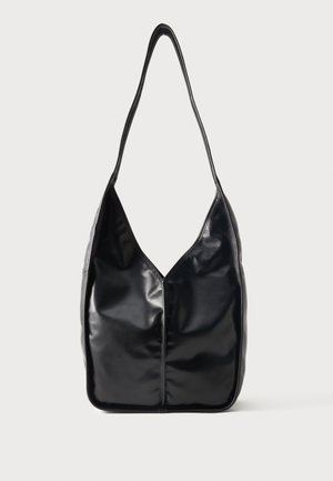 Μαύρη γυαλιστερή δερμάτινη τσάντα ώμου με ένα φαρδύ ιμάντα και μαλακό, χαλαρό ορθογώνιο σχήμα σε απλό φόντο.