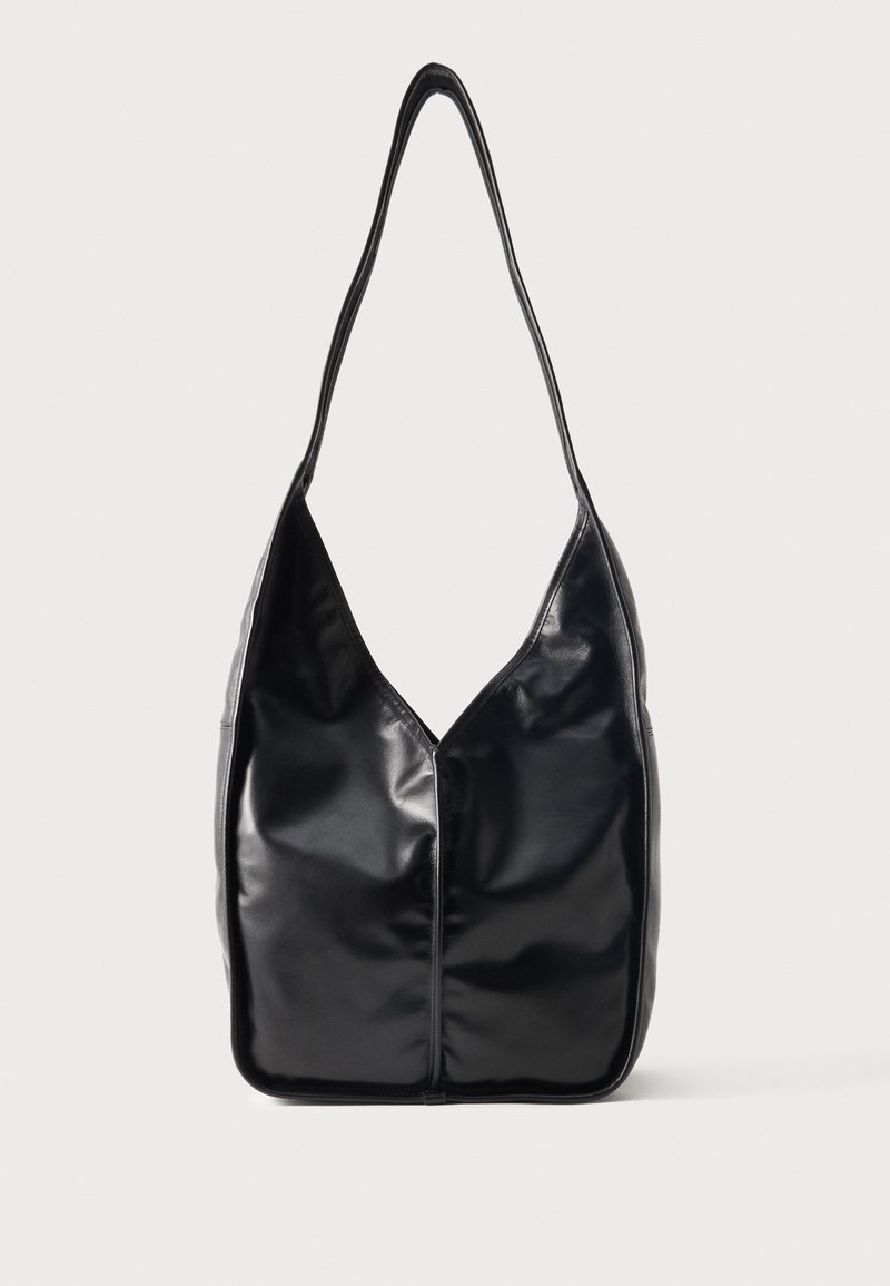 Μαύρη γυαλιστερή δερμάτινη τσάντα ώμου με ένα φαρδύ ιμάντα και μαλακό, χαλαρό ορθογώνιο σχήμα σε απλό φόντο.