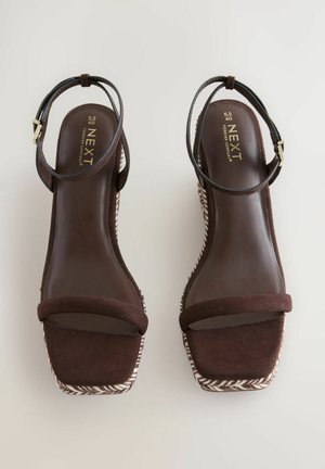 Barna velúr wedge szandálok platform kialakítással, barna bokapánttal és texturált fehér-barna szőtt talppal.
