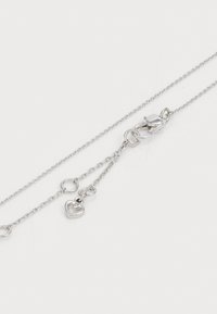 Colar de corrente prateado com fecho tipo lagosta, design em elos, e dois pendentes em forma de coração em comprimentos variados. Textura suave e acabamento polido.