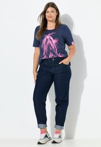 Námořnické tričko s ilustrací růžového psa, spárované s tmavě modrými džínami a vícebarevnými teniskami s růžovými akcenty.