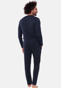 Completo da casa blu navy realizzato in tessuto morbido, composto da maglia a maniche lunghe e pantaloni abbinati con vestibilità comoda e tasche.