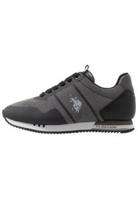 Chaussure de sport noire et grise en matériaux mesh et cuir synthétique, dotée d'une semelle texturée et d'un accent logo sur le côt é.