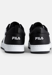 Zapatillas FILA en blanco y negro con parte superior de cuero texturizado, cuello acolchado, tira de agarre y suela blanca en contraste. Logo exhibido de manera prominente.