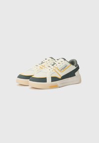 Laag uitgesneden sneakers met een crème kleurig mesh bovenwerk, groene suede accenten, gele details, witte veters en een getextureerde rubberen zool.