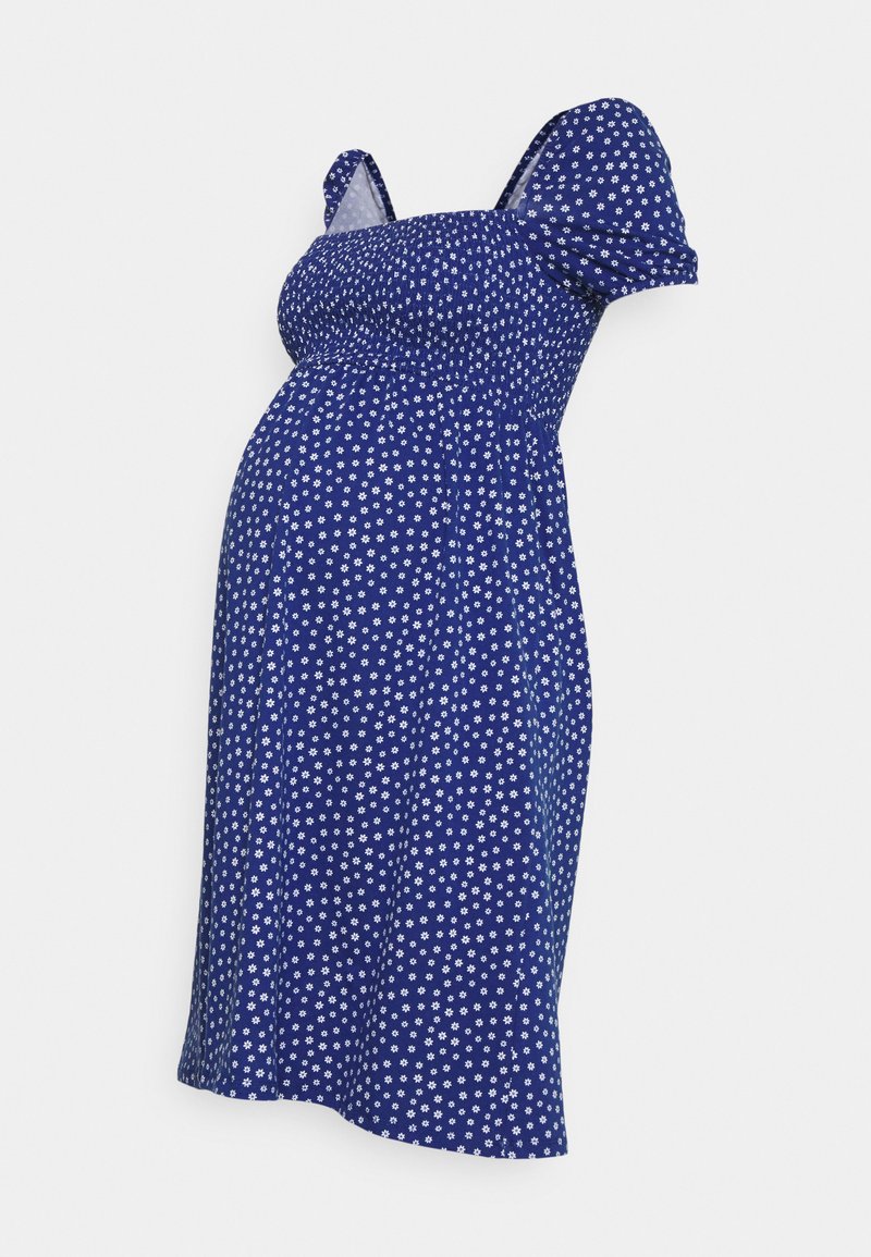 Vestido de maternidade azul com bolinhas brancas, mangas curtas bufantes e corpete pregueado. Tecido suave, design até ao joelho e corte solto.