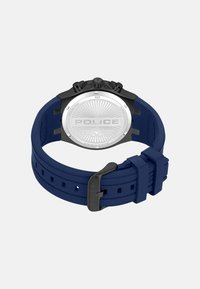 Mėlynas silikoninis dirželis laikrodis su juodu korpusu ir sidabriniu nugarėle, turintis apvalų dizainą ir "POLICE" logotipą ciferblate.