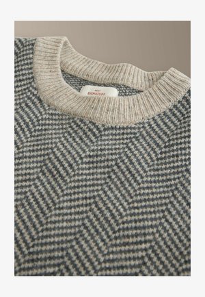 Harmaa ja kerma värvi neule, millel on kalaschenni mustriga ja ribadeta ümar kaelus. Materjal tundub kudumise ja tekstuuriga. Sildid on nähtavad seest.