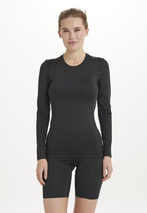 Svart långärmad träningsskjorta med rund halsringning, figursydd design och slät tyg; ihop med svarta shorts, vilket skapar en samordnad outfit.
