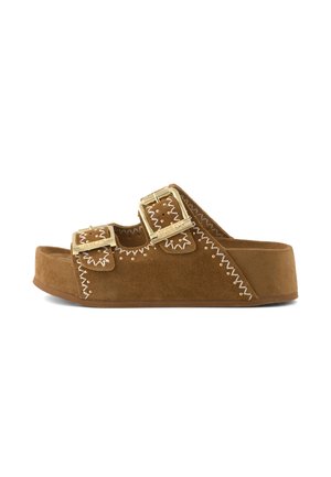 Sandalo con plateau in camoscio marrone con due fibbie dorate e cuciture decorative bianche su sfondo bianco.