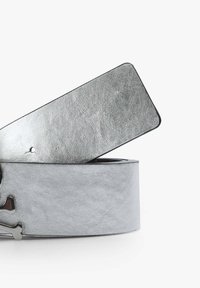 Silberner Kunstledergürtel mit glatter Oberfläche, rechteckigem Ende und einer Metallbuckle in Form eines Schädels. Mit einem schwarzen Rand akzentuiert.