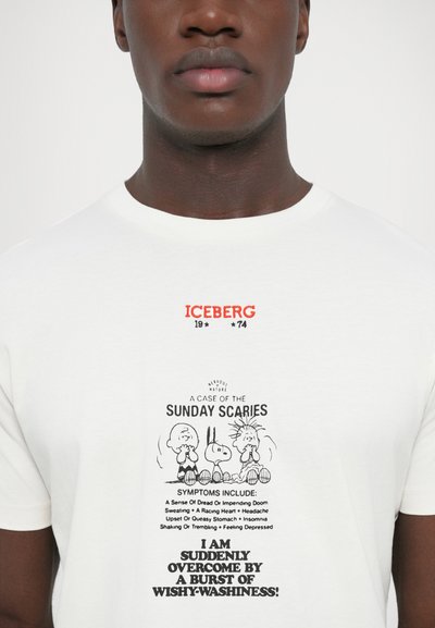 Camiseta blanca de algodón con texto y gráficos impresos en colores. El diseño incluye personajes de dibujos animados y frases humorísticas en el centro.