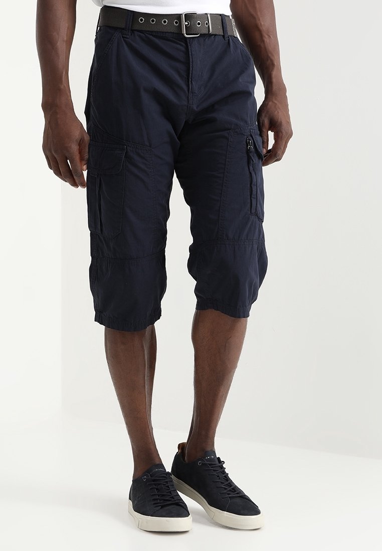 Shorts cargo bleu marine en tissu léger avec plusieurs poches, poignets élastiques et une taille lisse. Portés avec des baskets noires.