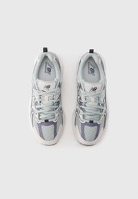 Light blue running shoes featuring mesh upper, white accents, and a reflective logo. Simplistic design with flat laces and reinforced heel.