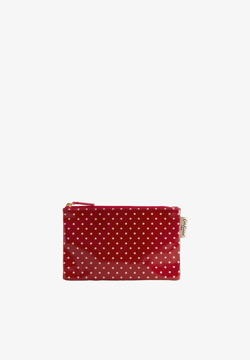 Trousse rectangulaire rouge avec fermeture éclair, pois blancs et une étiquette en tissu crème sur le côté.