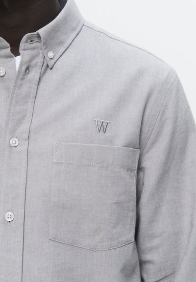 Chemise grise à boutons en mélange de coton, avec une poche sur la poitrine et la lettre "W" brodée. Texture douce avec un design de col classique.