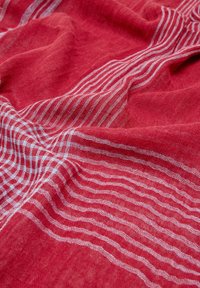 Czerwony len z białymi paseczkami; miękka tekstura i luźny splot tworzą płynny wygląd. Brak widocznych, wyraźnych krawędzi.