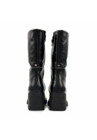 Bottes noires en cuir verni montantes, avec une finition texturée, un talon carré et une fermeture éclair à l'arrière ; accentuées par de petits détails métalliques sur les côtés.
