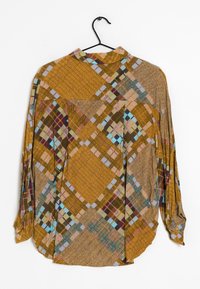 Chemise à manches longues en marron et moutarde, présentant un motif géométrique avec des couleurs et des textures variées. Comprend un col et des détails de poche avant.