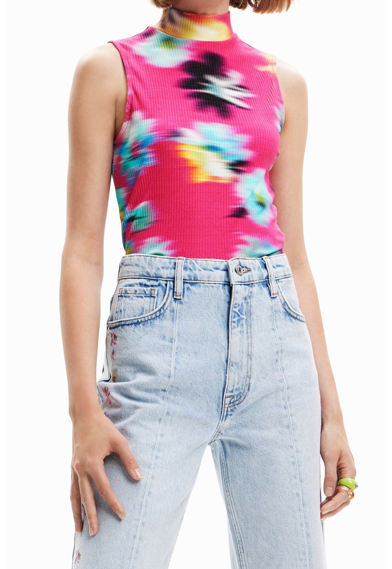 Haut sans manches rose vif avec motifs floraux multicolores associé à un jean taille haute bleu clair sur une personne.