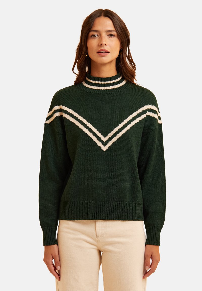 Maglione verde a maglia con colletto alto, caratterizzato da strisce a zig zag bianche in contrasto sul petto. I polsini e l'orlo a coste aggiungono texture.