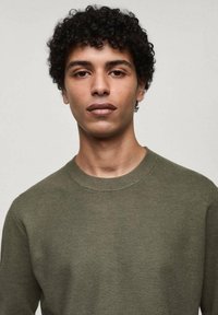 Maglione a maglia verde oliva con colletto a girocollo a coste, motivo testurizzato e forma leggermente aderente. Nessun logo o decorazione visibile.