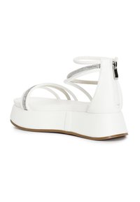 White platform sandals with multiple thin straps and a back zipper. Features a silver accent on the straps and a textured sole.