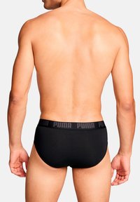 Schwarze Herrenunterwäsche aus weichem Stoff, mit einem strukturierten Bund, der mit "PUMA" in schwarzer Schrift gekennzeichnet ist. Passform: eng.
